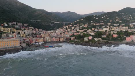 Sea-waves-breaking-on-rocky-coast-with-houses-in-Genoa-city-harbor