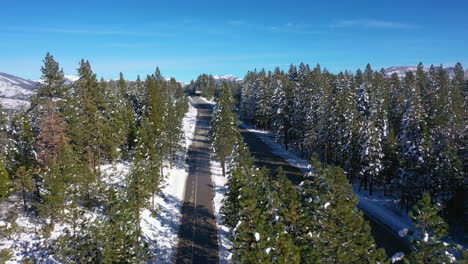 Drone-shot-over-traffic-on-the-I-80-in-the-snowy-mountains-of-sunny-Tahoe,-USA