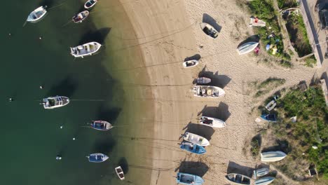Aerial-top-down-forward-over-many-fisher-boats-docked-on-sand-beach