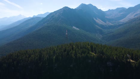 Drone-shot-flying-around-a-high-voltage-pylon-standing-atop-a-large-hill-in-the-italian-Alps