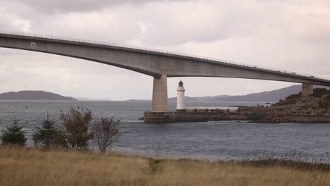 bridge-taking-you-over-the-water-with-a-light-house-driving-towards-Isle-of-Skye,-hIghlands-of-Scotland