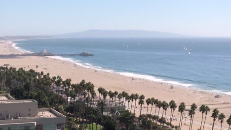 Luftaufnahme-über-Dem-Strand-Von-Santa-Monica-Mit-Einer-Reihe-Von-Palmen-Und-Dem-Berühmten-Pier-An-Bewölkten-Tagen