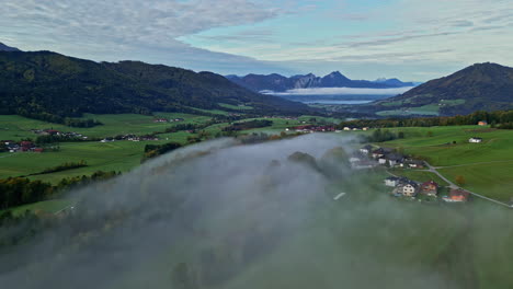 Aerial-view-backwards-over-the-foggy-countryside-of-Attersee,-fall-day-in-Austria