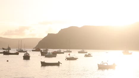 boats-floating-in-a-flowing-harbor-at-sunset-in-Portree-on-Isle-of-Skye,-hIghlands-of-Scotland