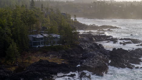 Drone-video-at-sunset-in-Ucluelet-British-Columbia,-Canada-over-the-ocean-and-forest-with-a-ocean-front-cabin