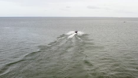 Jet-ski-skims-across-the-sea-surface,-leaving-frothy-trail-in-its-wake