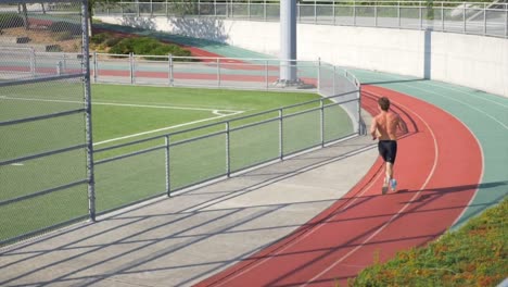 Topless-Man-With-Sportive-Body-Running-On-Outdoor-Tracks-Of-Stadium