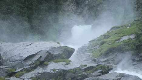 Clouds-of-white-steam-rise-from-bottom-of-waterfall-and-rugged-rock