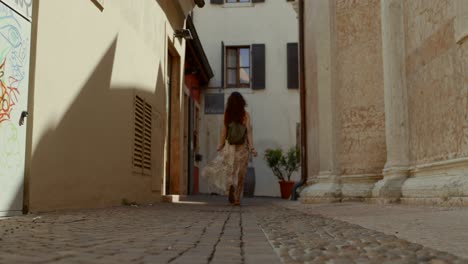 Female-tourist-walks-through-alley-in-ancient-city-center,-verona
