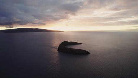 Amazing-slow-aerial-shot-through-clouds-over-the-Pacific-ocean-with-Molokini-Crater-and-the-sacred-island-of-Kaho'olawe-in-the-distance-during-amazing-sunset-on-Maui,-Hawai'i