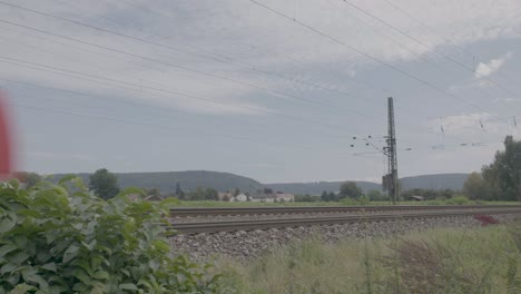 Red-passenger-train-in-motion,-daytime,-blurred-motion-effect,-rural-landscape-backdrop
