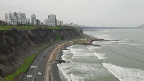 Coastal-allure-of-Miraflores,-Lima:-Drone-glides-over-the-highway,-capturing-the-vibrant-energy-of-the-district
