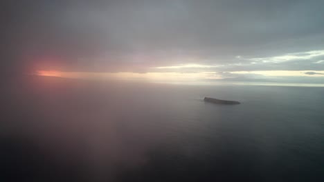Cinematic-slow-aerial-shot-through-clouds-over-the-Pacific-ocean-with-Molokini-Crater-and-the-sacred-island-of-Kaho'olawe-in-the-distance-during-amazing-sunset-on-Maui,-Hawai'i