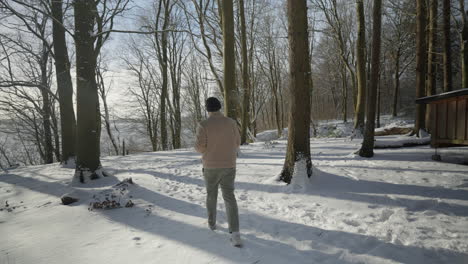 Winter-walk-in-sunshine,-man-enjoying-a-hot-drink-in-a-snowy-forest