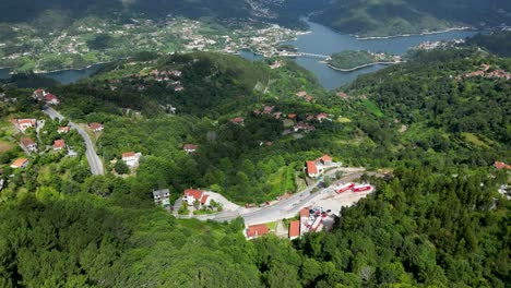 Aerial-Perspective-of-Hillside-Residences-in-Gerês-National-Park,-Portugal,-with-Caniçada-Dam-Against-a-Sunny-Sky,-Parque-Nacional-Peneda-Gerês