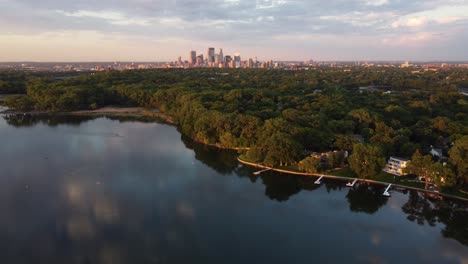 Drone-push-in-towards-skyline-of-Minneapolis-from-Cedar-Lake-during-a-summer-sunset-4k
