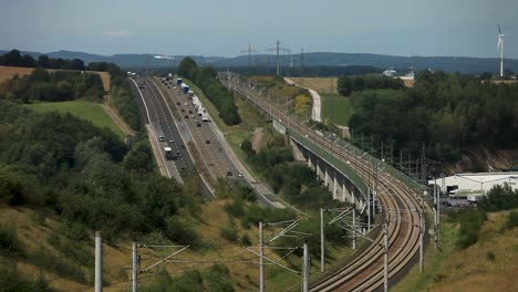 Multi-transport-route-with-cars-on-highway-and-train-on-tracks-in-rural-area