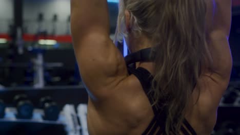 Slow-motion-shot-of-a-fit-girls-back-while-she-works-out-doing-tricep-extensions-over-head-in-front-of-the-mirror