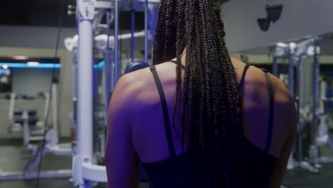 Aufnahme-Des-Rückens-Eines-Sportlichen-Mädchens,-Während-Sie-In-Einem-Leeren-Fitnessstudio-An-Einem-Kabelgerät-Trainiert