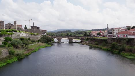 aerial-over-cavado-river-leading-to-Medieval-bridge,-Barcelos-Portugal