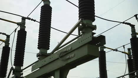Close-up-of-high-voltage-electrical-insulators-at-a-power-station,-overcast-sky-in-the-background