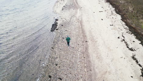 Aerial-view-of-jogger-on-beach-path-on-a-overcast-day