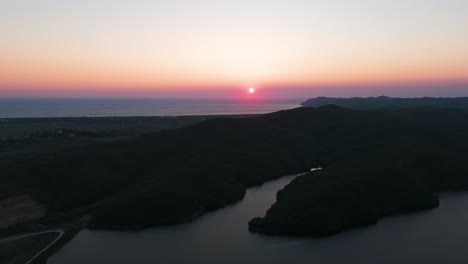 Colorful-aerial-sunset-over-Adriatic-sea-and-dark-shadow-hillside-near-river