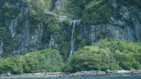 Captivating-waterfall-hidden-amidst-lush-bushes-in-the-breathtaking-landscape-of-Milford-Sound