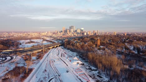 Drone-Push-In-of-Minneapolis-Minnesota-skyline-during-winter-golden-hour-from-the-Cedar-Lake-Trail-4k