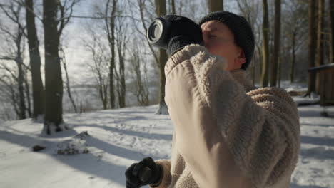 Person-In-Winterkleidung-Genießt-An-Einem-Verschneiten-Tag-Ein-Heißes-Getränk-Im-Freien,-Wärmt-Sich-In-Der-Kälte-Auf-Und-Genießt-Die-Natur