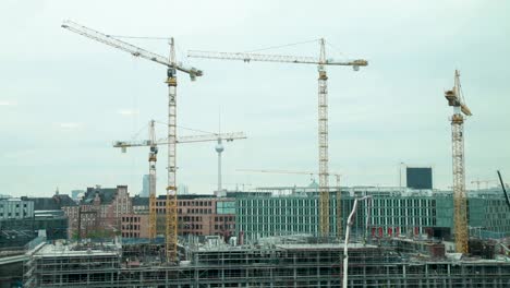 Baukräne-Ragen-über-Einer-Baustelle-In-Berlin-Auf,-Im-Hintergrund-Der-Berühmte-Fernsehturm
