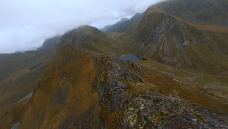 FPV-Drone-Aerial-of-a-mountain-crest,-flying-through-the-clouds,-Lofoten-Islands-in-Norway,-impressive-low-flight