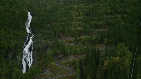 Drohne-Fliegt-über-Die-Serpentinenzufahrtsstraße-Zur-Trolltunga-Wanderung-Neben-Einem-Wasserfall