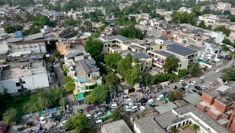 Aerial-profile-view-of-Cheema-Heart-Complex-with-lots-of-visitors-beside-a-busy-jammed-street-situated-at-Gujranwala,-Punjab,-Pakistan
