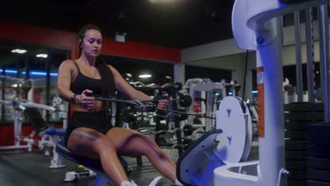 Athletic-girl-working-out-on-a-row-machine-in-the-gym-in-slow-motion