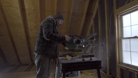 Man-cutting-wood-with-mitre-saw-in-a-workshop,-sawdust-flying,-focused-craftsmanship
