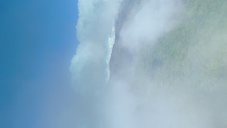 Wolkendurchflug-Mit-Berghintergrund,-Durch-Die-Wolken-Fliegende-Cockpitansicht-Mit-Dichten-Immergrünen-Waldbergen-Und-Blauem-Himmel,-Echtes-Vertikales-4K-Luftbildvideo-Für-Soziale-Medien,-9:16-Porträtmodus