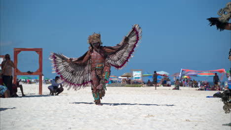 Slow-motion-of-a-dancer-dressed-up-as-a-mayan-eagle-warrior-performing-and-jumping-on-the-sand-at-a-beach-in-Mexico
