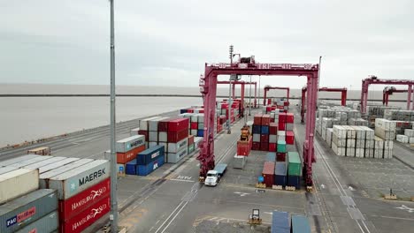 Aerial-view-of-cargo-containers-at-a-busy-port-with-trucks-and-cranes,-overcast-day-at-port-of-Buenos-Aires