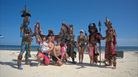 Slow-motion-shot-of-a-family-posing-with-a-company-of-dancers-performing-as-mayan-warriors