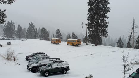 Vehicles-and-school-buses-parked-in-the-mountainous-Bogus-Basin-ski-field-car-park-with-snow-covered-landscape-in-Boise,-Idaho,-USA
