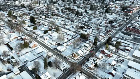 Aerial-establishing-shot-of-American-city,-small-town-covered-in-winter-snow-blizzard