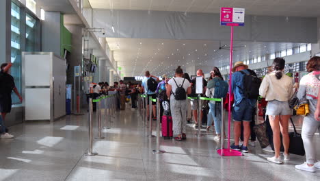 Menschen,-Die-Am-Gate-In-Der-Schlange-Stehen,-Um-Am-Internationalen-Flughafen-Von-Malaga-Ein-Flugzeug-Zu-Besteigen,-Starbucks-Im-Hintergrund,-Urlaubszeit,-4K-Aufnahme