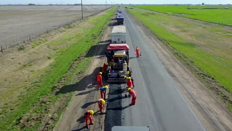Aerial-view-of-workers-in-high-visibility-clothing-paving-road-in-rural-area-near-Buenos-Aires