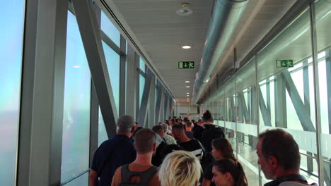 People-waiting-in-line-to-board-an-airplane-in-Malaga-international-airport,-people-queuing,-holiday-vacation-time,-4K-shot