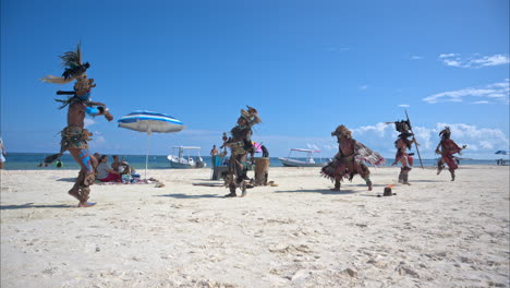 Cámara-Lenta-De-Una-Compañía-De-Baile-En-Cancún-México-Actuando-Como-Guerreros-Mayas-En-La-Playa-En-Un-Día-Soleado