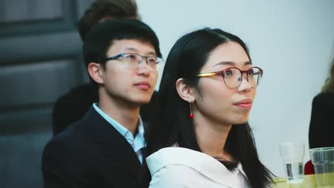 Close-up-of-faces-Asian-man-and-woman-in-meeting-room-listening-to-speaker