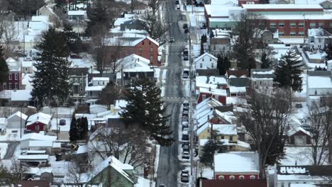 Long-aerial-zoom-of-truck-traveling-through-American-city-covered-in-winter-snow