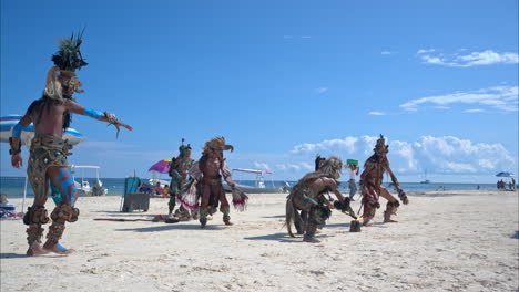Zeitlupe-Einer-Als-Maya-Krieger-Verkleideten-Tanzgruppe,-Die-An-Einem-Hellen,-Sonnigen-Nachmittag-Am-Strand-Von-Cancun,-Mexiko,-Auftritt
