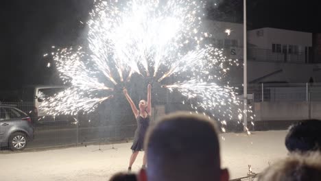 Hand-held-shot-of-a-performer-dancing-with-multiple-fireworks-at-a-show